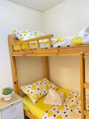 a bedroom with two bunk beds with yellow sheets at The Cozy Cove - 3BR with Netflix, Prime and KTV in Manila