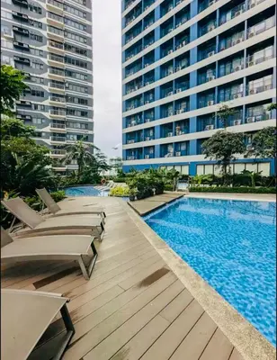 a swimming pool with chaise lounge chairs next to a building at d'DEN at SMDC AIR Makati 1BR Bay view in Manila