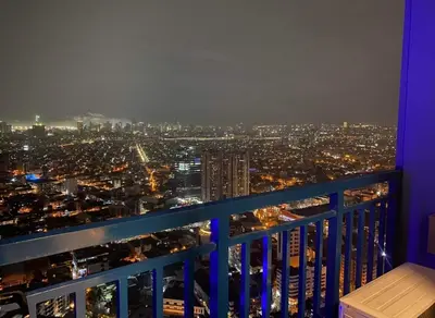 a view of a city at night from a balcony at d'DEN at SMDC AIR Makati 1BR Bay view in Manila