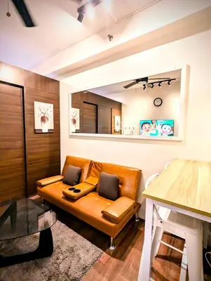 a living room with a couch with a laptop on it at d'DEN at SMDC AIR Makati 1BR Bay view in Manila