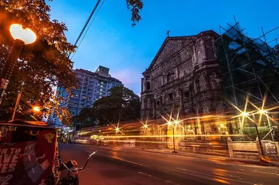an old building with lights on a street at night at 19f w NFLIX & BALCONY NEAR ROB, PGH, ACC USM&SLMC in Manila