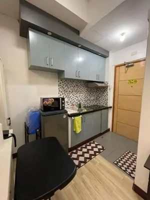 a small kitchen with a refrigerator and a table at 19f w NFLIX & BALCONY NEAR ROB, PGH, ACC USM&SLMC in Manila