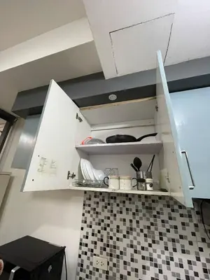 a kitchen with white cabinets and black and white tiles at 19f w NFLIX & BALCONY NEAR ROB, PGH, ACC USM&SLMC in Manila