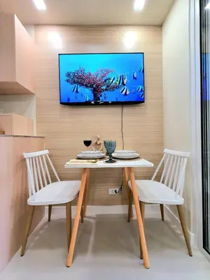 a dining room with a table and two chairs and a tv on a wall at Lovely, Cozy One Bedroom with Wi-fi Pool in Pasig in Manila