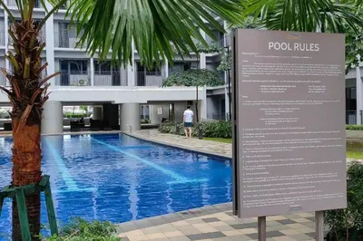 a sign next to a swimming pool in front of a building at Franchelle Bliss - Shore 2 Residences Tower 1 in Manila