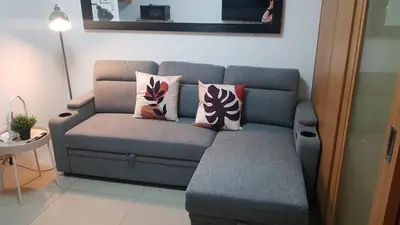 a grey couch with pillows in a living room at Newly Renovated Shell Residences Mall of Asia Condo in Manila