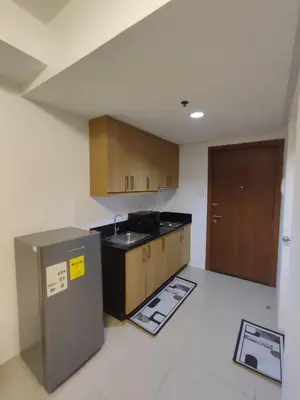 an empty kitchen with wooden cabinets and a sink at Newly Renovated Shell Residences Mall of Asia Condo in Manila