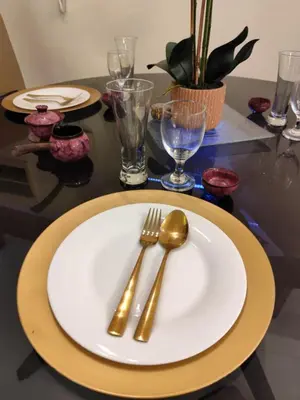 a table with a white plate with a gold spoon and fork at Velvet Accommodation PH in Manila