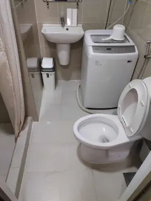 a white bathroom with a toilet and a sink at Qween E Choice 2 Qween bed Condo in Manila