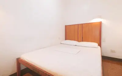 a small bedroom with a bed with a wooden headboard at Stay Malate Hostel by RedDoorz in Manila