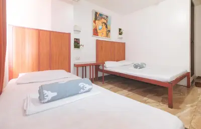 a room with two beds and a table in it at Stay Malate Hostel by RedDoorz in Manila