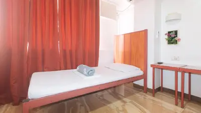 a small room with a bed and a curtain at Stay Malate Hostel by RedDoorz in Manila
