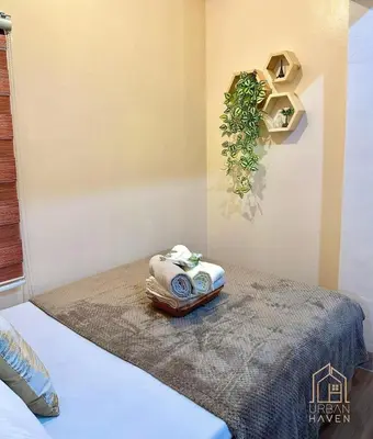 a room with a bed with a towel and a phone at Staycation in Alabang in Manila