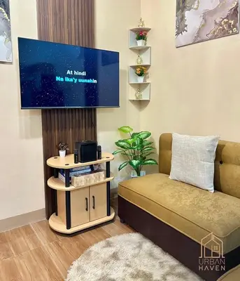 a living room with a bed and a tv at Staycation in Alabang in Manila