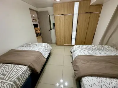two beds in a small room with a door at Kathys Crib 2Bedroom MOA View at Shell Residence in Manila