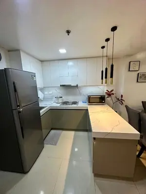 a kitchen with white cabinets and a stainless steel refrigerator at Kathys Crib 2Bedroom MOA View at Shell Residence in Manila