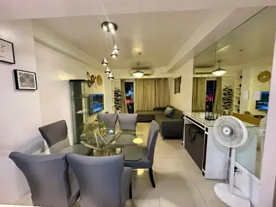 a dining room and living room with a table and chairs at Kathys Crib 2Bedroom MOA View at Shell Residence in Manila