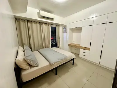 a small bedroom with a bed and white cabinets at Kathys Crib 2Bedroom MOA View at Shell Residence in Manila