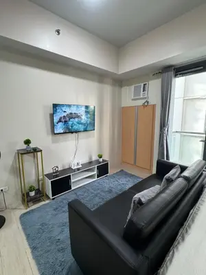 a living room with a black couch and a tv at 81 Newport Boulevard Condominium across International Airport Terminal 3 C1-4C in Manila