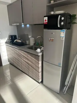 a kitchen with a microwave on top of a refrigerator at Spacious Apartment Hotel near City of Dreams, Airport, MOA, Okada, Ayala Malls, and Solaire Casino with free 5 pool access in Manila