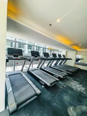 a gym with a row of treadmills and tables at Spacious Apartment Hotel near City of Dreams, Airport, MOA, Okada, Ayala Malls, and Solaire Casino with free 5 pool access in Manila