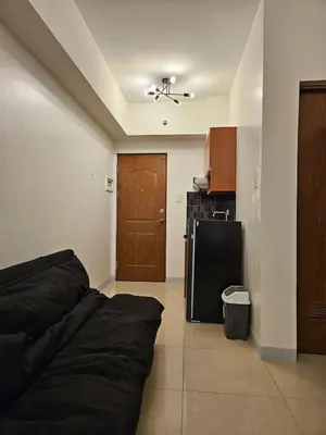 a living room with a black couch and a kitchen at Kintai Suites at the Beacon in Manila