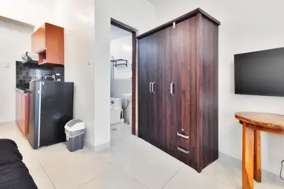 a bathroom with a large wooden cabinet and a tv at Kintai Suites at the Beacon in Manila