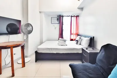 a bedroom with a bed and a desk and a chair at Kintai Suites at the Beacon in Manila