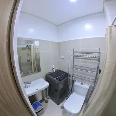 a bathroom with a sink and a toilet and a mirror at MAKATI - Lush Residences in Manila
