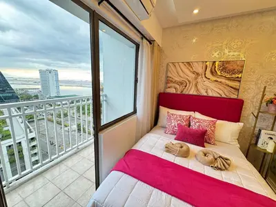 a bed in a room with a large window at Shore Residences Sunset Room facing Manila Bay & City View RM1641 by Prime Stay MOA in Manila