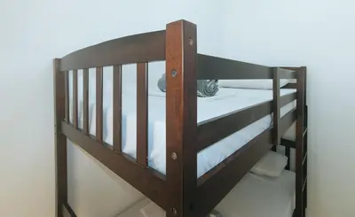 a wooden bunk bed with white sheets on it at Stay Manila Hotel by RedDoorz in Manila