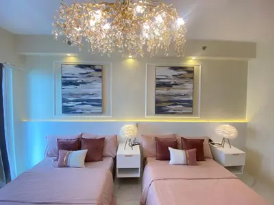 a living room with two beds and a chandelier at Fairy Dust Sky Suite By Crib2GO in Manila