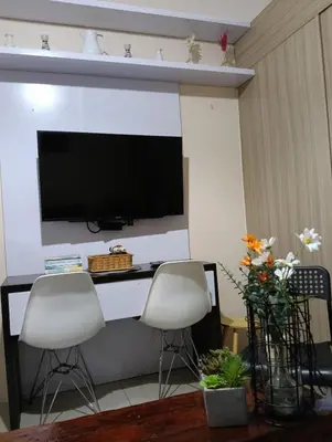 a living room with two chairs and a television on a wall at Shore Staycation near Moa & Airport in Manila