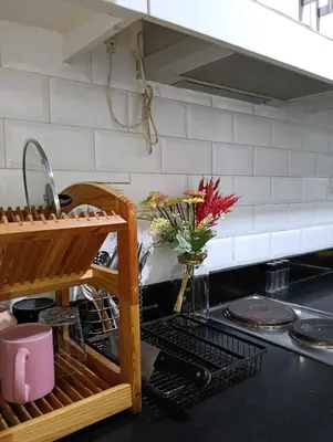 a kitchen counter with a dish drying rack and a sink at Shore Staycation near Moa & Airport in Manila