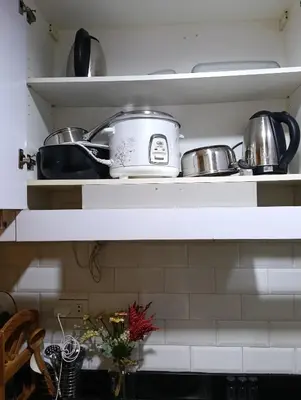 a kitchen shelf with pots and pans on it at Shore Staycation near Moa & Airport in Manila