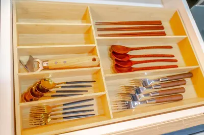 a wooden drawer filled with different types of knives at Éire Home Stay in Manila