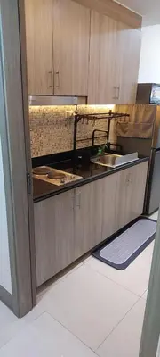 a kitchen with wooden cabinets and a sink at Fully Furnished 1 Bedroom Condo - Fame Residences, Tower 2 in Manila