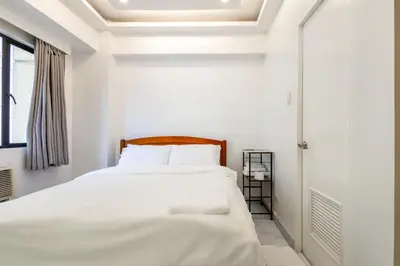 a white bedroom with a bed with white sheets at Forbeswood Heights BGC suite near st Lukes in Manila