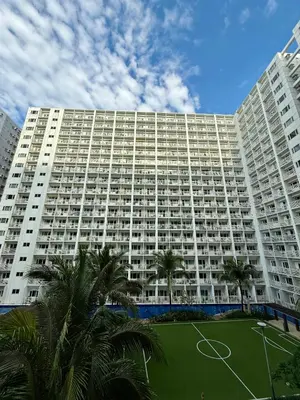 a large building with a soccer field in front of it at Modern Double-Sized Bed with Netflix & Pool View in Manila