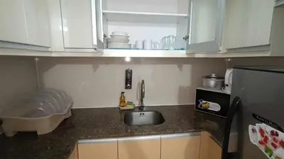 a small kitchen with a sink and a refrigerator at 81 Newport Boulevard across Manila Airport NAIA T3 in Manila