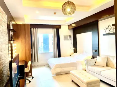 a hotel room with a bed and a couch at Cozy studio near Eastwood QC in Manila