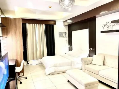 a hotel room with two beds and a tv at Cozy studio near Eastwood QC in Manila