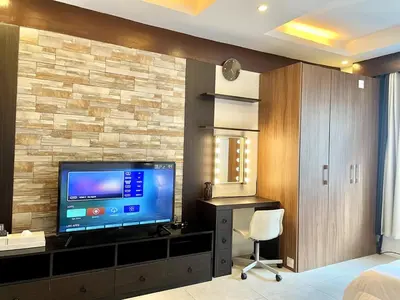 a bedroom with a television and a desk with a chair at Cozy studio near Eastwood QC in Manila