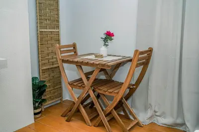 a wooden table and chair with a vase of flowers on it at TahananStays at Makati CBD in Manila