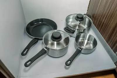 a group of pots and pans sitting on a shelf at TahananStays at Makati CBD in Manila