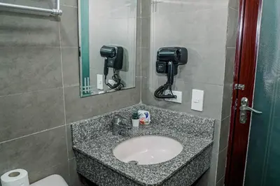 a bathroom with a sink and a mirror and a toilet at TahananStays at Makati CBD in Manila