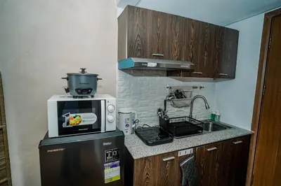 a small kitchen with a microwave on top of a refrigerator at TahananStays at Makati CBD in Manila