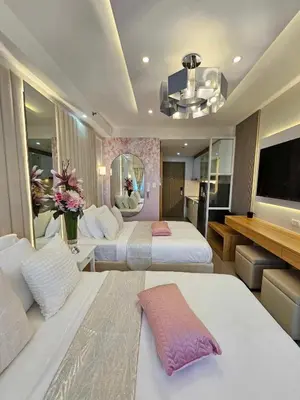 a hotel room with two beds and a flat screen tv at Graceful Getaway Suites in Manila