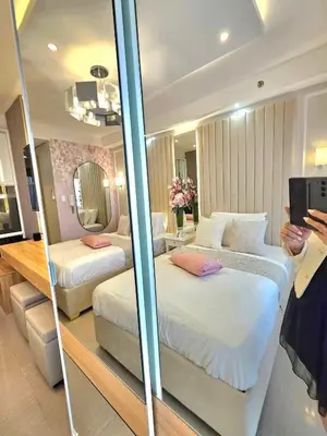 a woman taking a picture of a hotel room with two beds at Graceful Getaway Suites in Manila