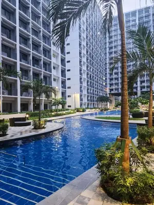 a swimming pool with palm trees and buildings at Graceful Getaway Suites in Manila